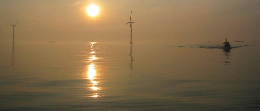 Off-shore wind mills and boat at sunset
